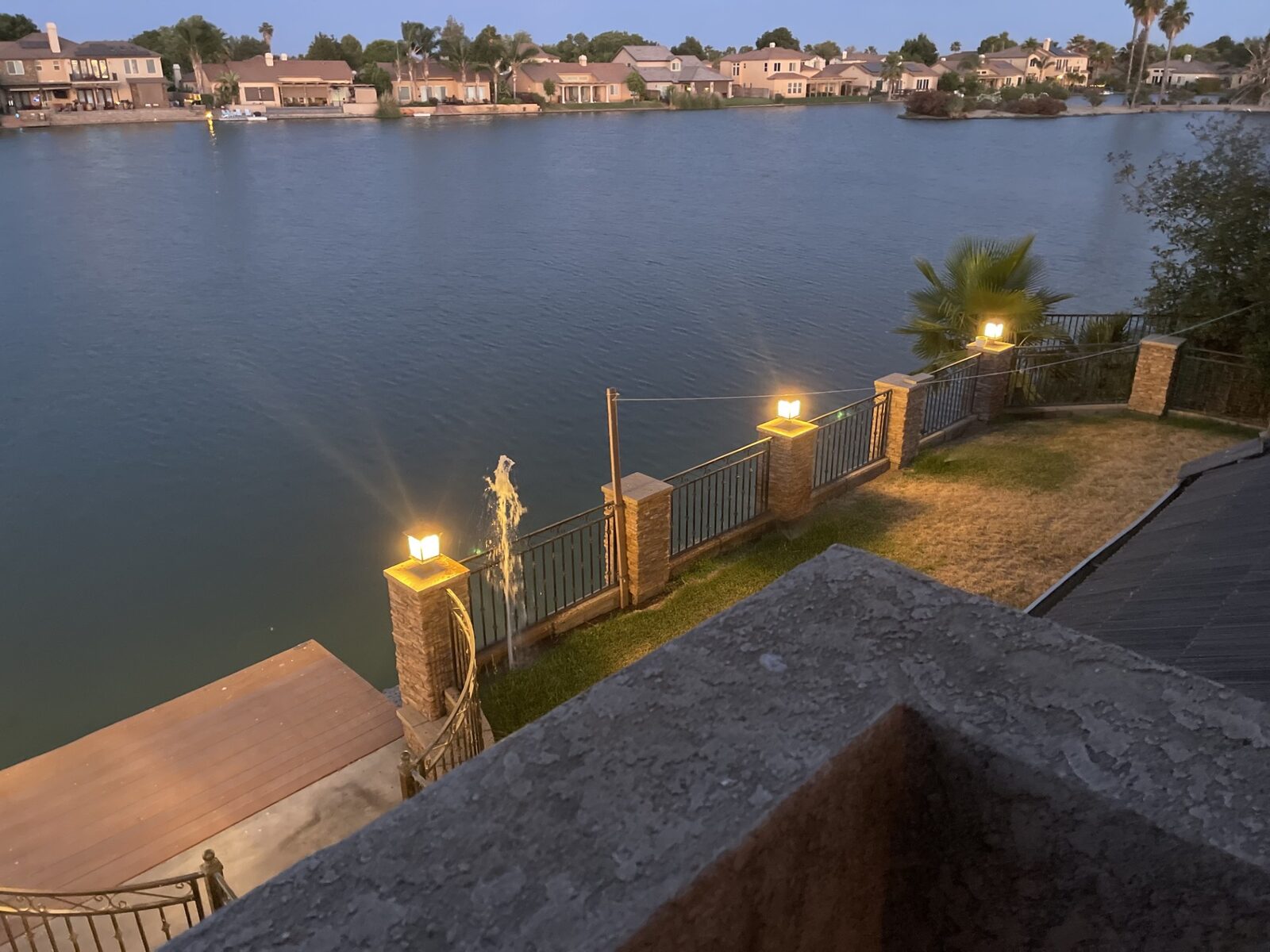Waterfront property at dusk with lit gate posts, California